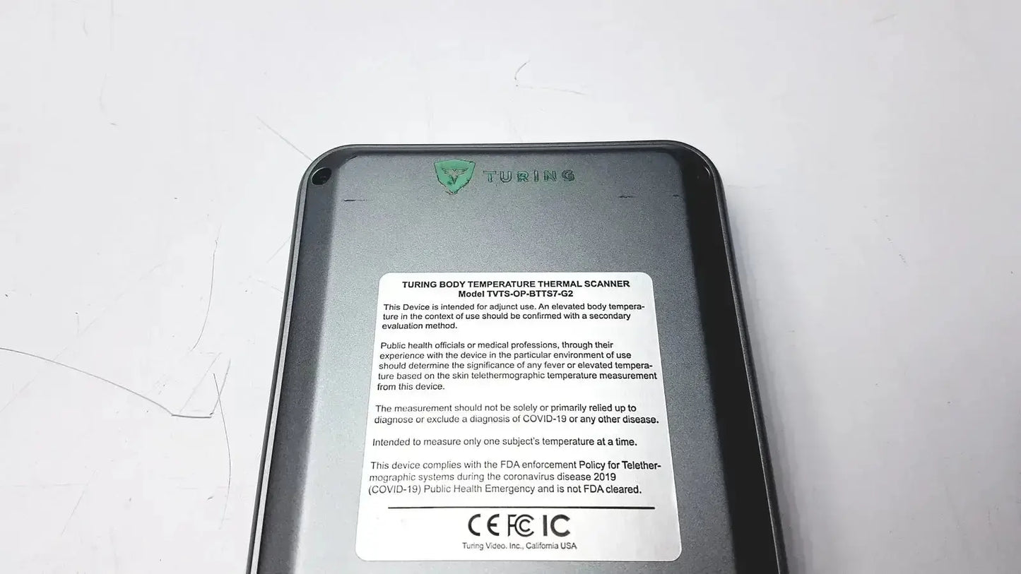 Black plastic turing body temperature thermal scanner with white label showing model number and regulatory information