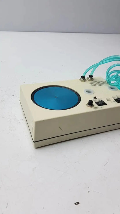 Beige rectangular unicorn medical md11684 desiccator vacuum with circular blue metallic disc and coiled teal tubing