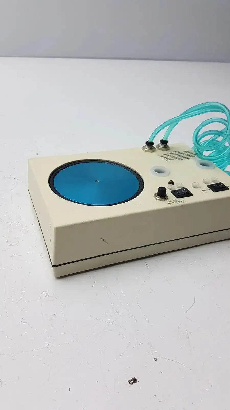Beige rectangular unicorn medical md11684 desiccator vacuum with blue circular platform and coiled teal tubing visible