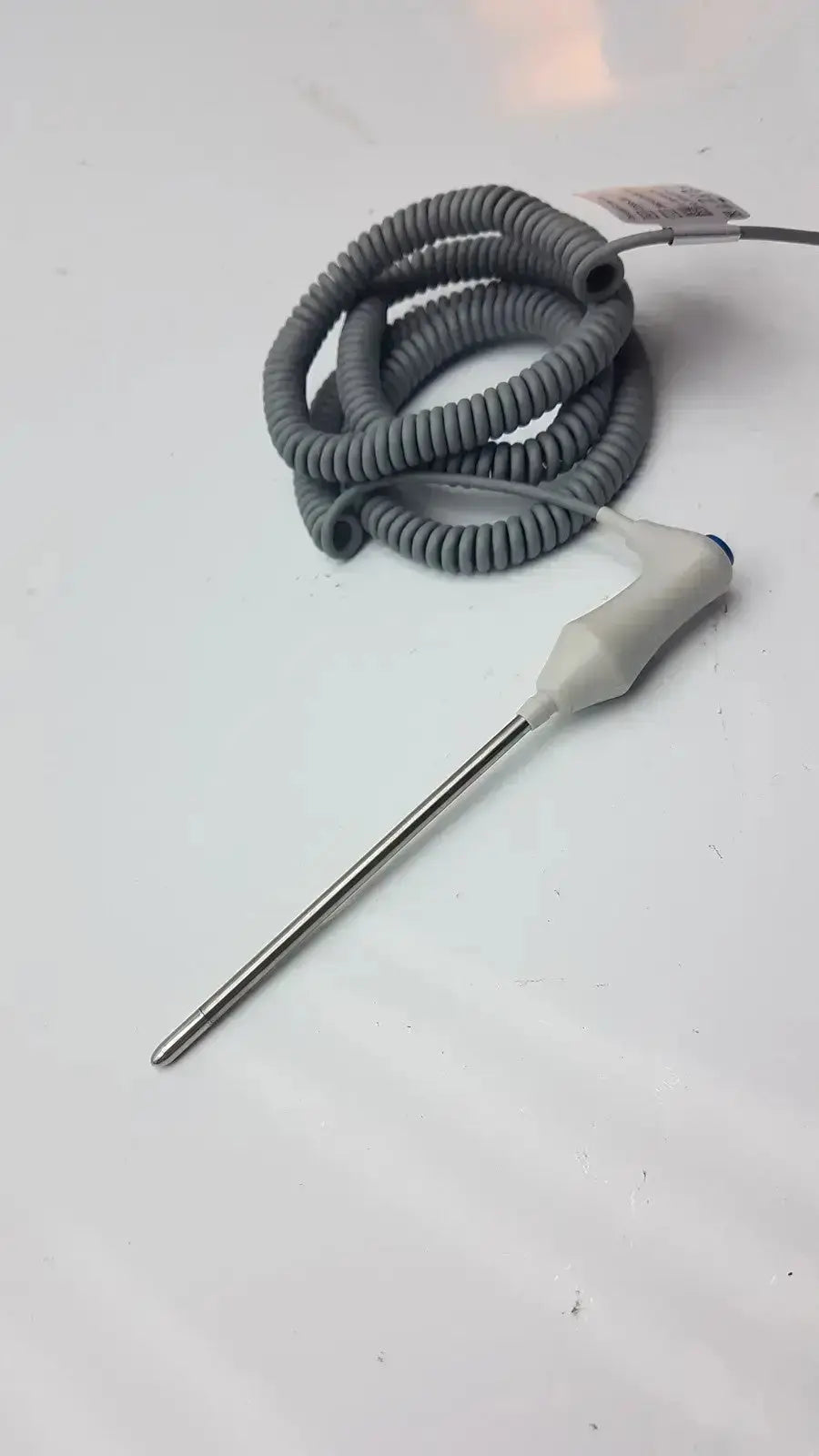 Gray coiled oral temperature probe with white plastic handle and metallic probe for accurate oral temperature measurement