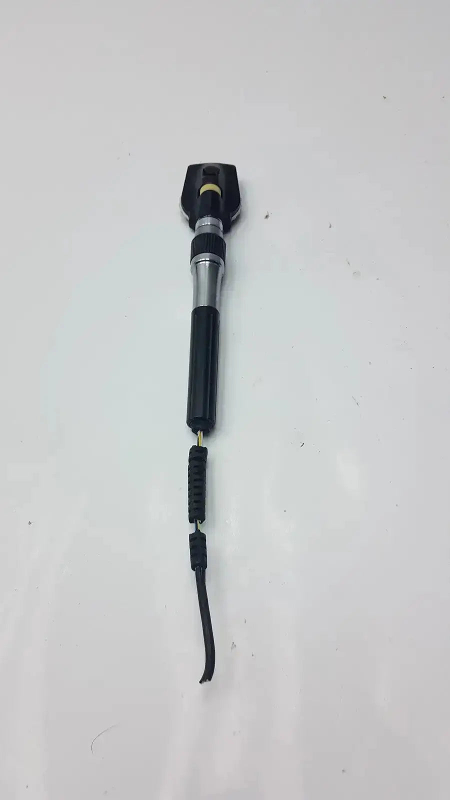 Black and silver welch allyn 3.5v ophthalmoscope head with textured grip and coiled cord for hospital surplus use