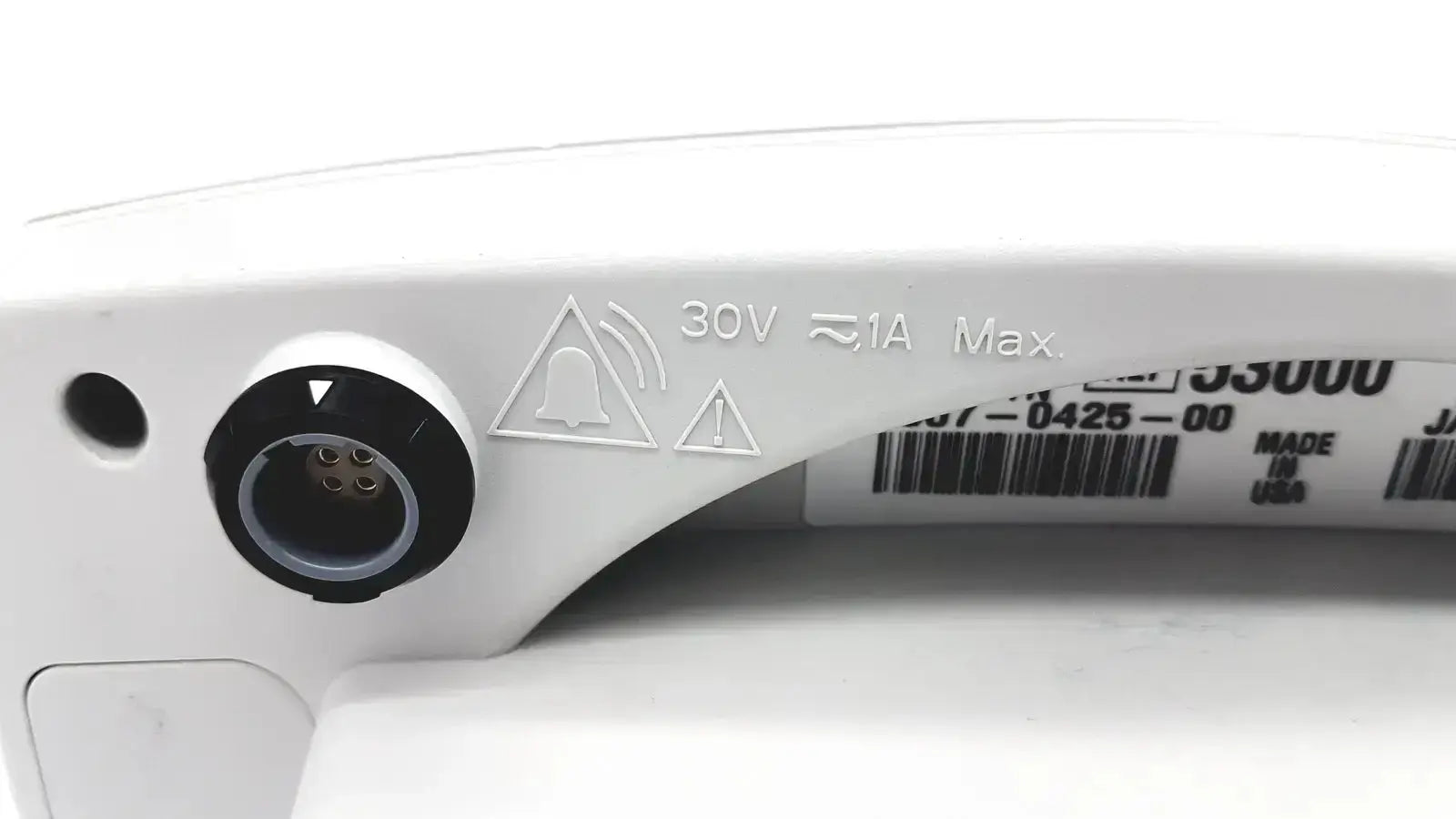 Back side of a white plastic power input port with black circular cover and safety markings on welch allyn vital signs monitor