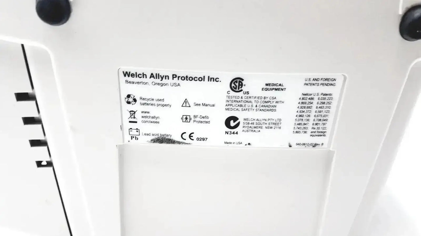 White plastic label with black text and symbols showing welch allyn protocol inc on welch allyn 530t0 patient monitor