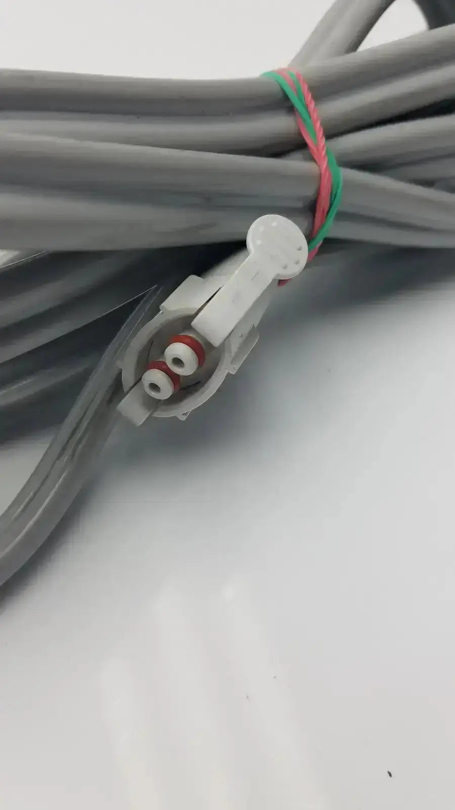 Gray welch allyn blood pressure hose with white locking connector and red white terminal screws bundled by green pink tie