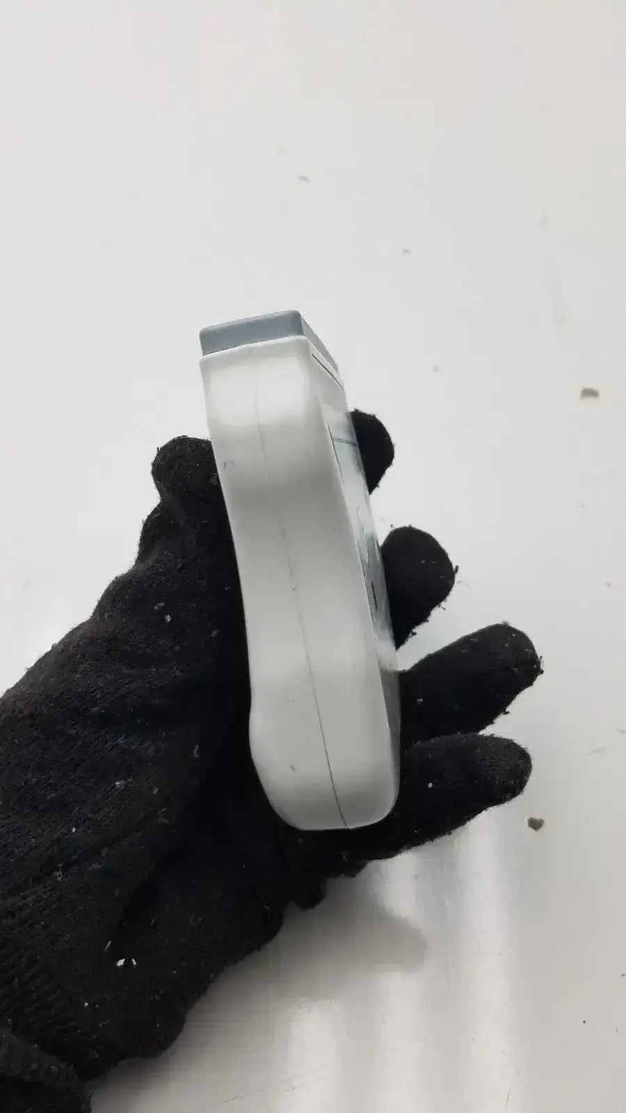 Silver-colored wireless ecg acquisition module held in black-gloved hand for welch allyn digital health monitoring