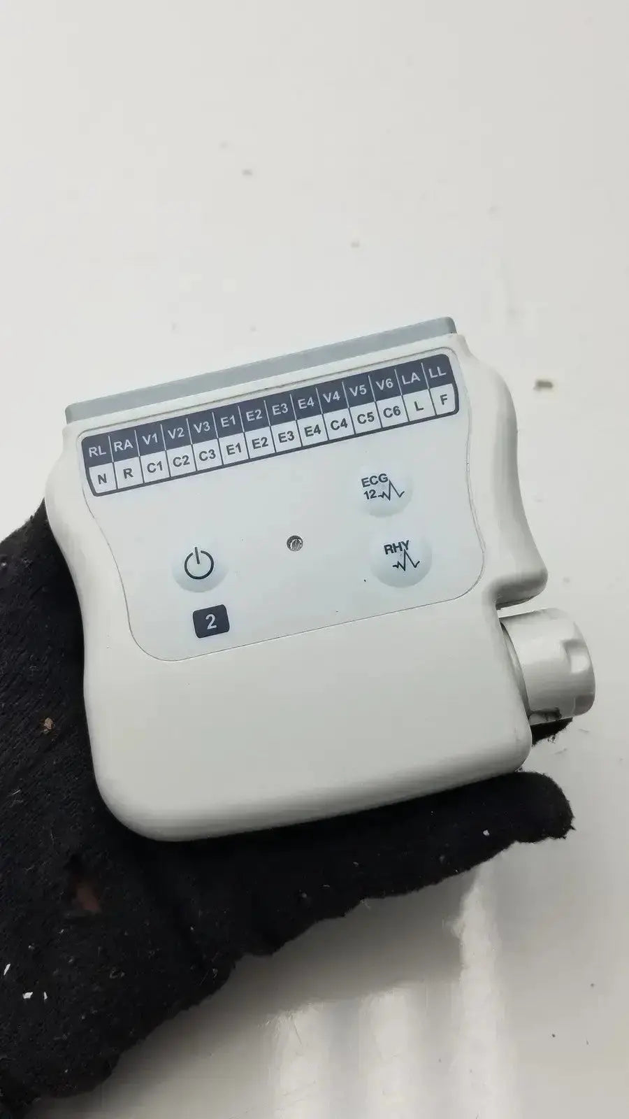 White plastic welch allyn wireless ecg acquisition module with labeled electrode pads and a silver control knob