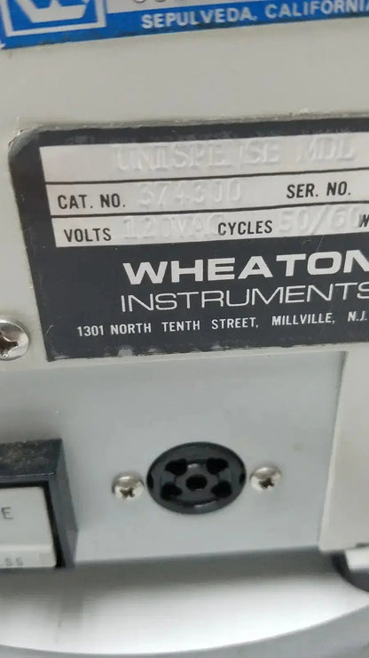 Gray wheaton instruments industrial equipment label with black text and blue logo showing unispense ii dose catalog number 374310