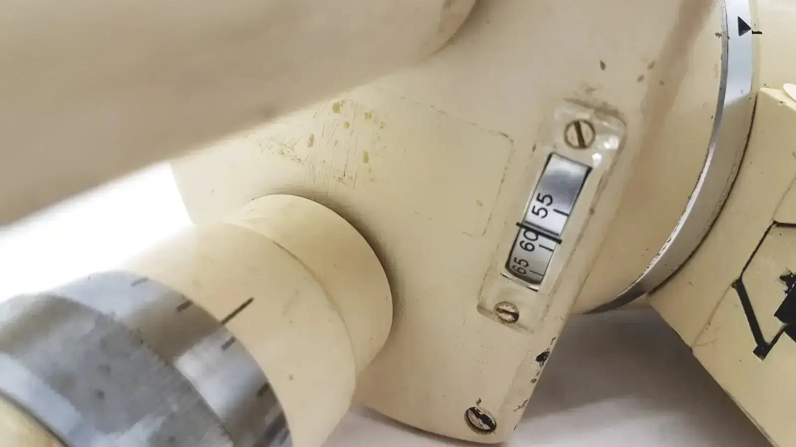 Cream-colored slightly worn mechanical device with silver dial and numerical markings on wild heerbrugg m5-26436 microscope