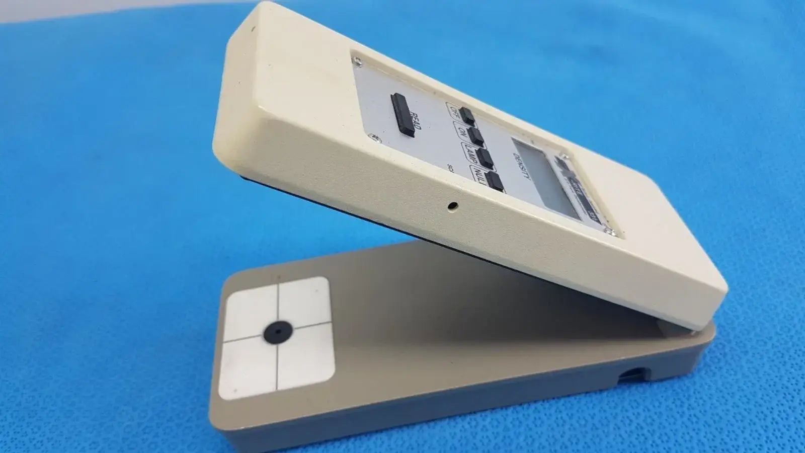 Cream-colored plastic battery operated x-rite 331 transmission densitometer with gray base and black buttons for precision measuring