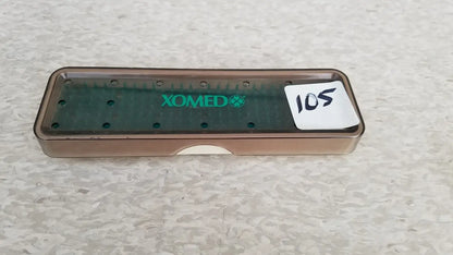 Brown plastic xomed poly vac dental instrument tray with green branding and circular holes for reuse medical equipment sterilization
