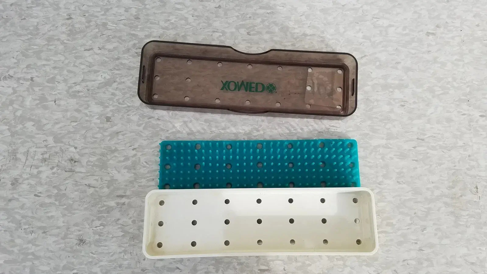 Brown plastic xomed poly vac tray with green logo and perforated surface for reuse medical equipment sterilization