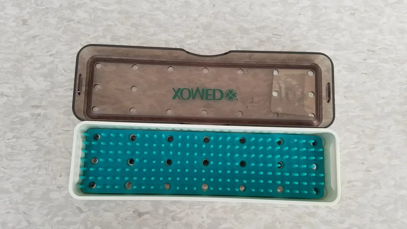 Teal and white plastic xomed poly vac sterilization case with translucent brown lid for reuse medical equipment storage