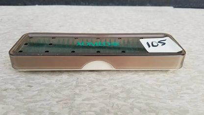 A translucent brown plastic xomed poly vac medical equipment sterilization case with a green logo and circular indentations