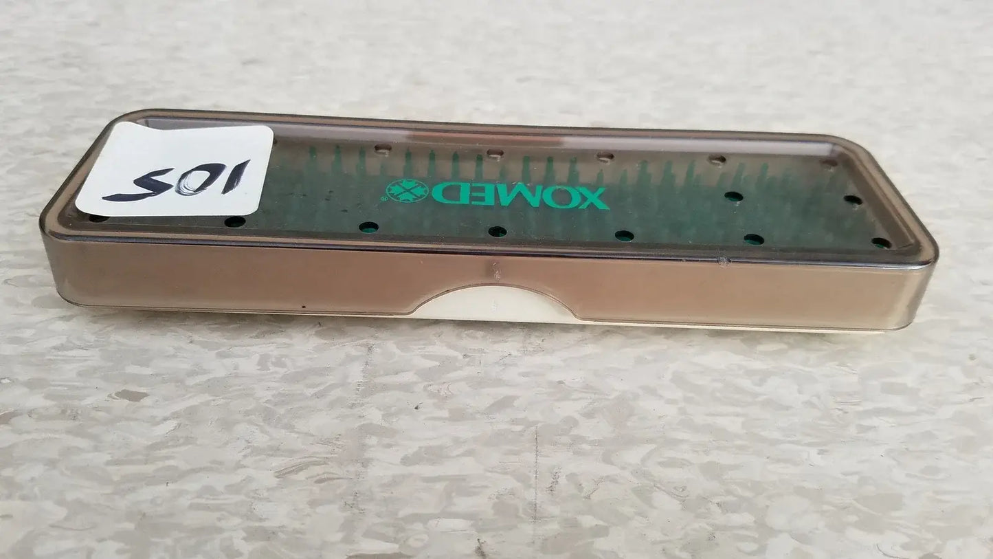 Transparent brown plastic xomed poly vac dental instrument tray with green branding and multiple slots for medical equipment