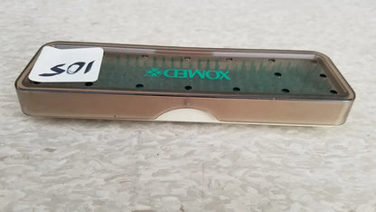 Transparent brown plastic xomed poly vac dental instrument tray with green branding and multiple slots for medical equipment
