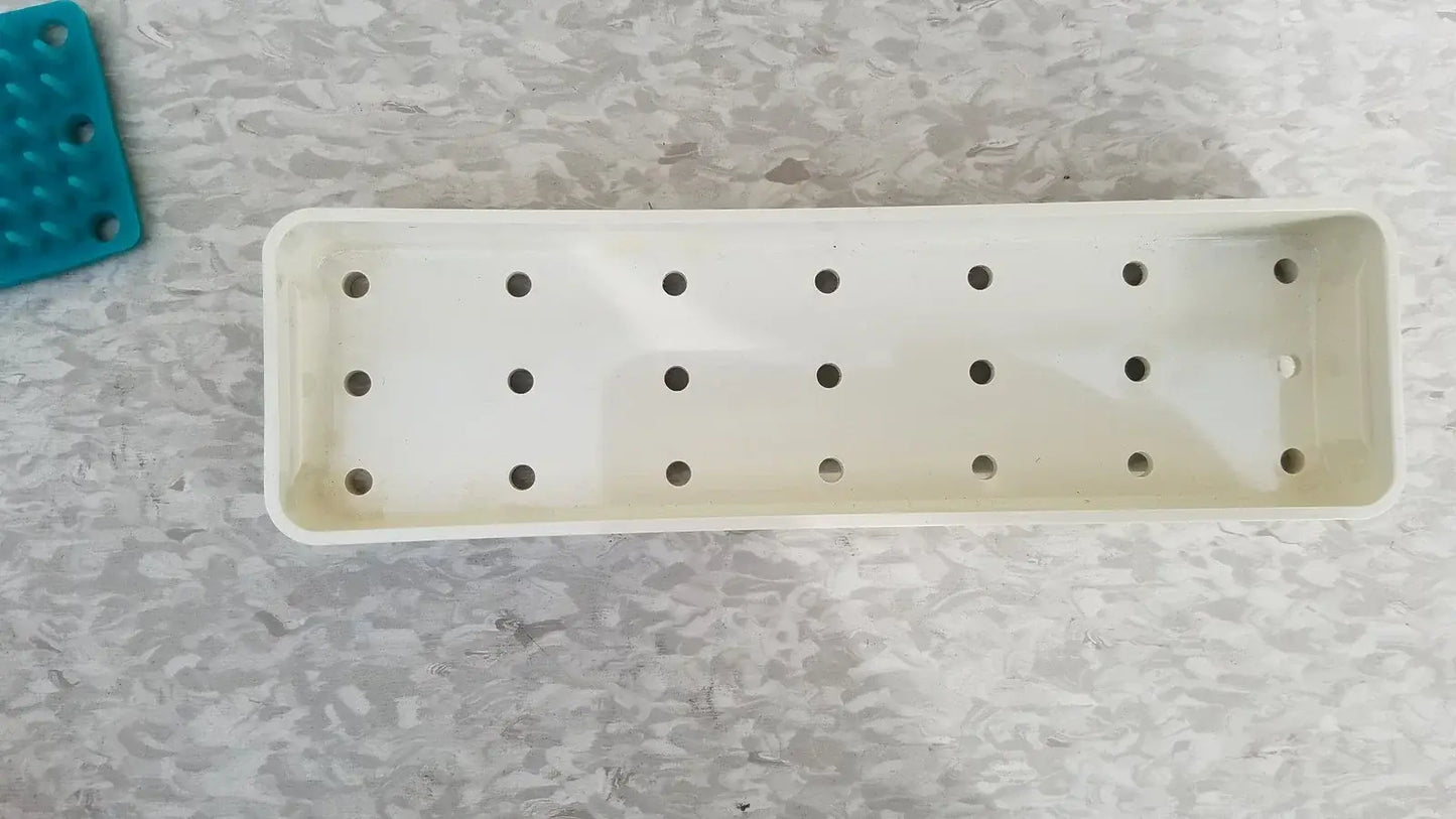 White rectangular plastic plant tray with evenly spaced holes for reuse medical equipment in xomed poly vac sterilization case