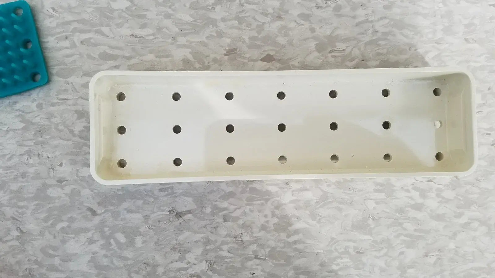 White rectangular plastic plant tray with evenly spaced holes for reuse medical equipment in xomed poly vac sterilization case