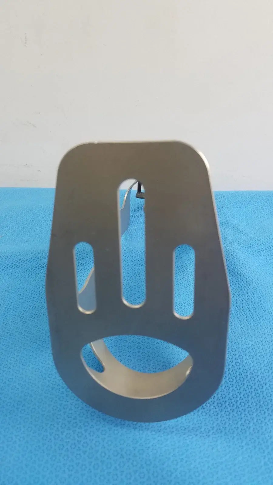 Black metal bracket with three vertical slots and circular base for Zimmer orthopedic Biomet Finneli tensioning medical equipment