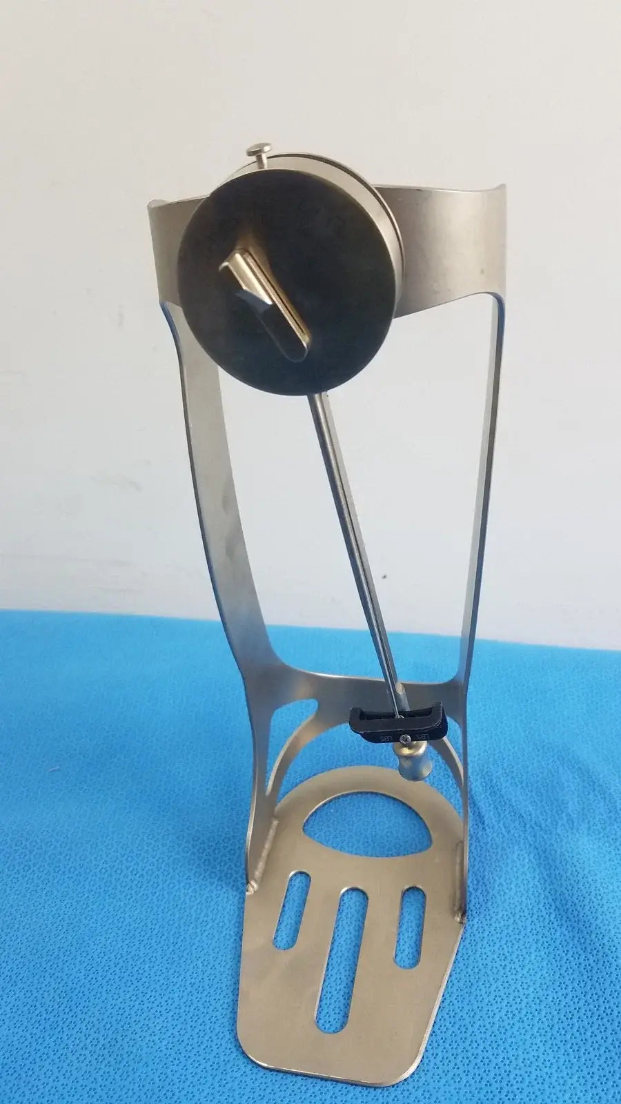 Silver metallic bicycle water bottle cage with circular clamp and adjustable strap for biomet finneli tensioning medical equipment