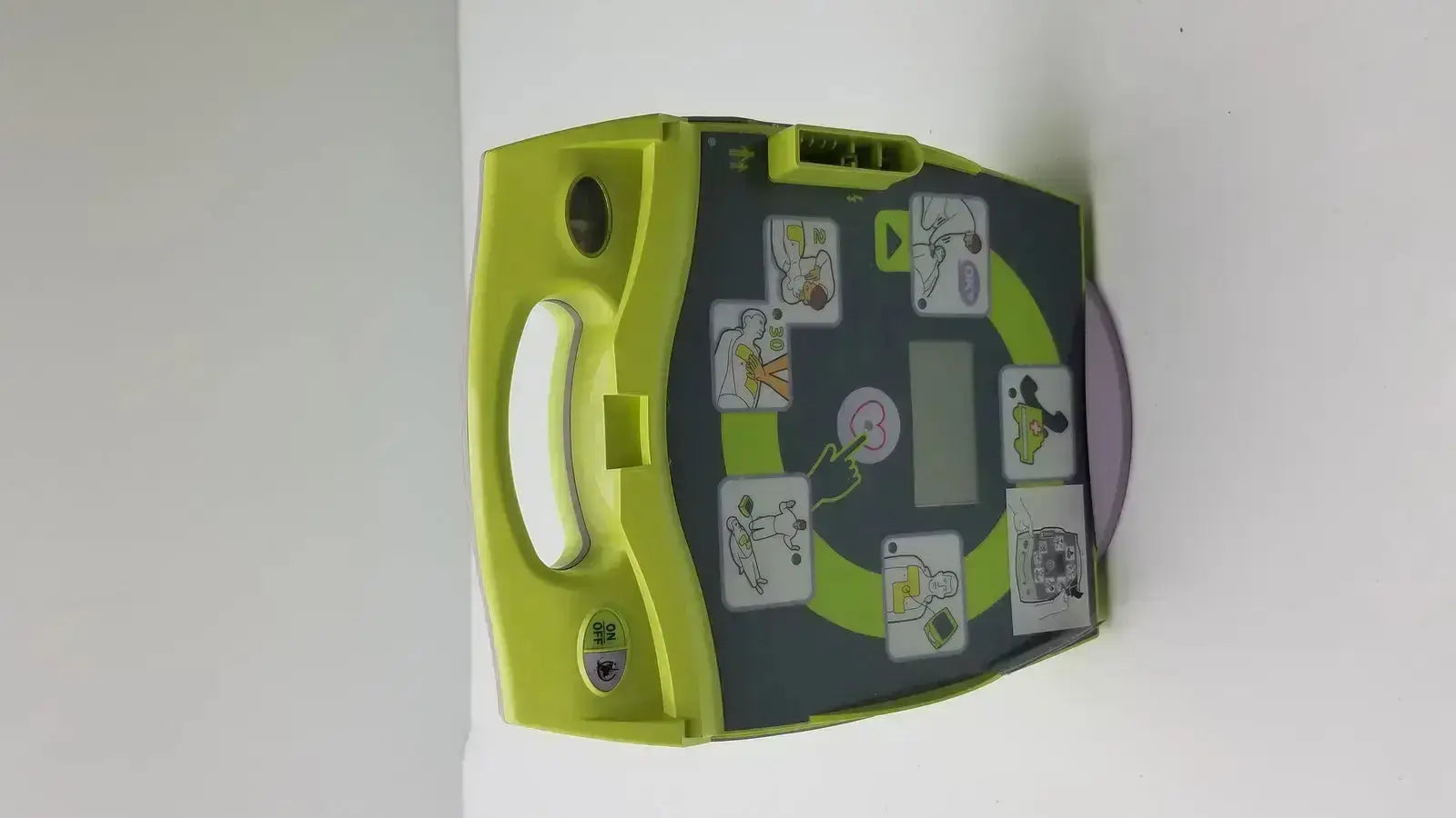 Lime green and dark gray zoll aed plus defibrillator with instructional diagrams for emergency cardiac use