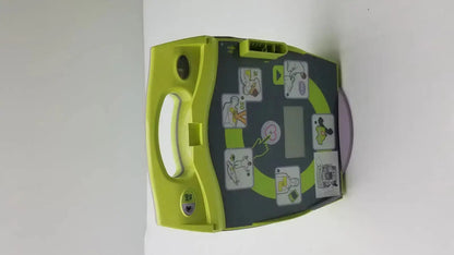 Lime green and dark gray zoll aed plus defibrillator with instructional diagrams for emergency cardiac use