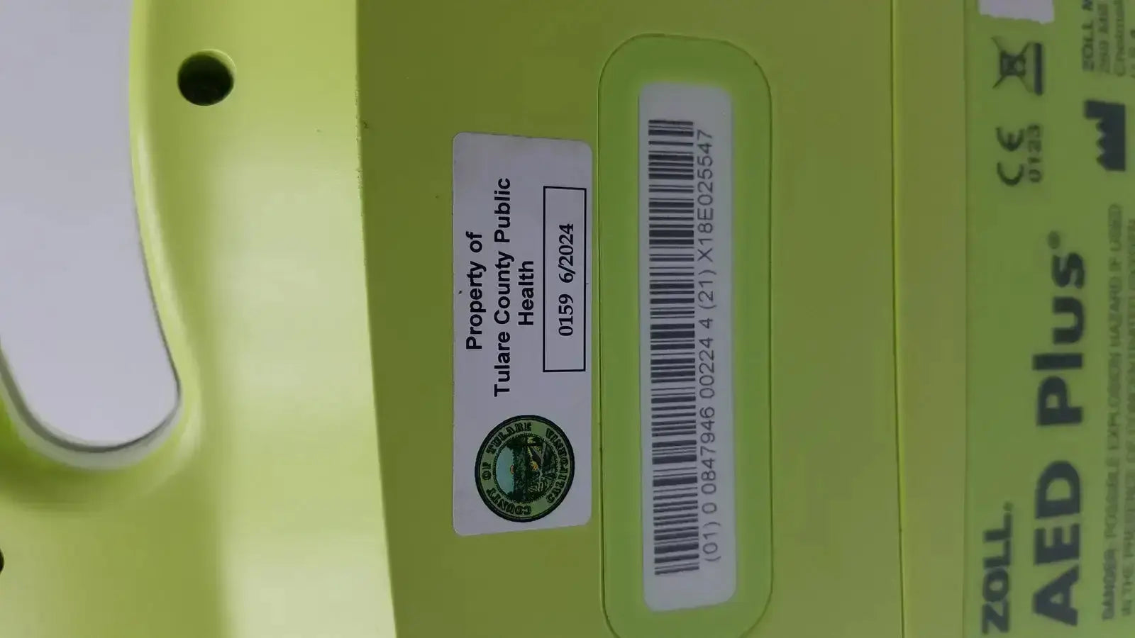Lime green zoll aed plus automated external defibrillator with barcode and tulare county public health property label