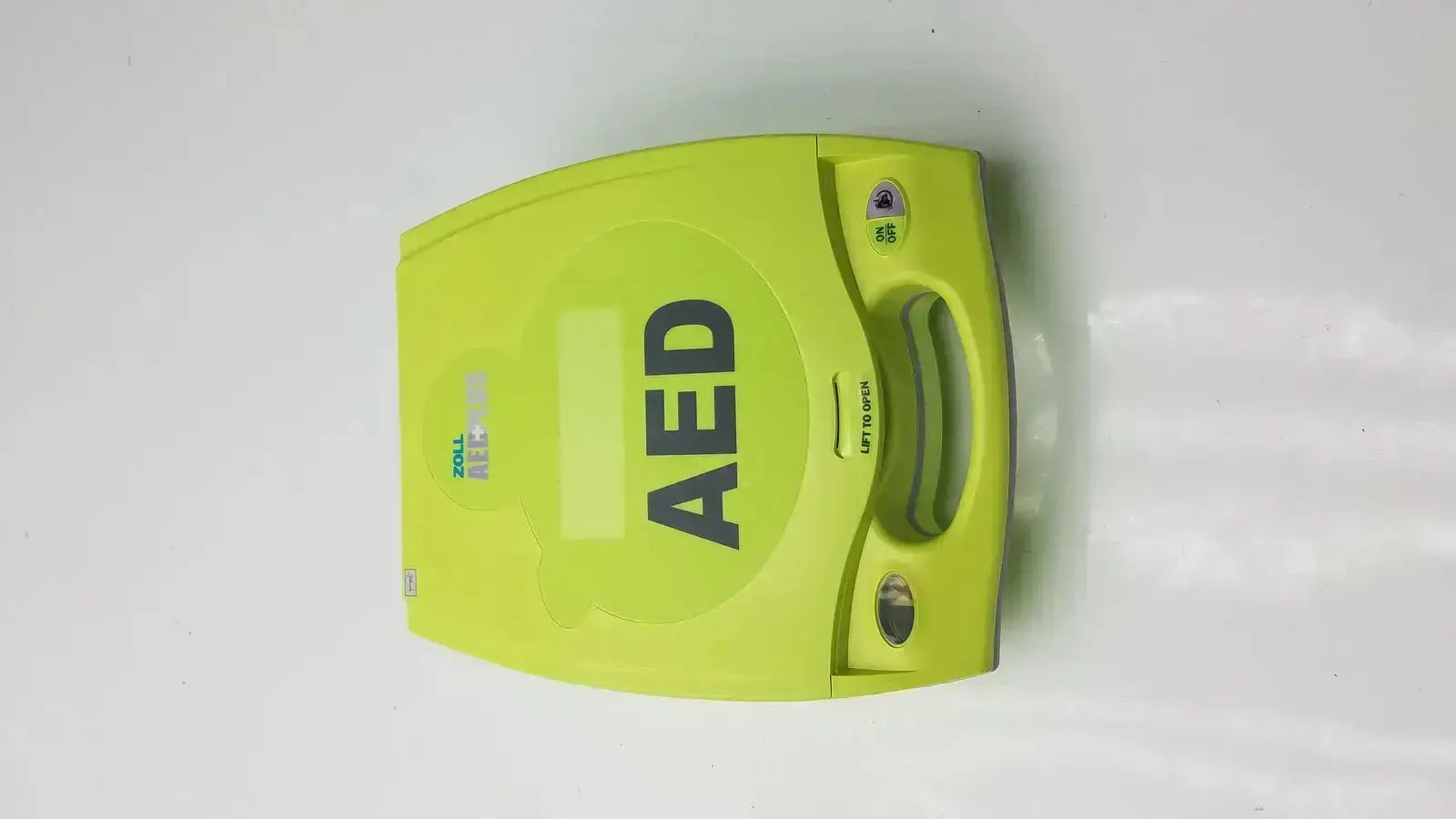 Bright lime green ZOLL AED Plus defibrillator with handle and control panel designed for emergency use