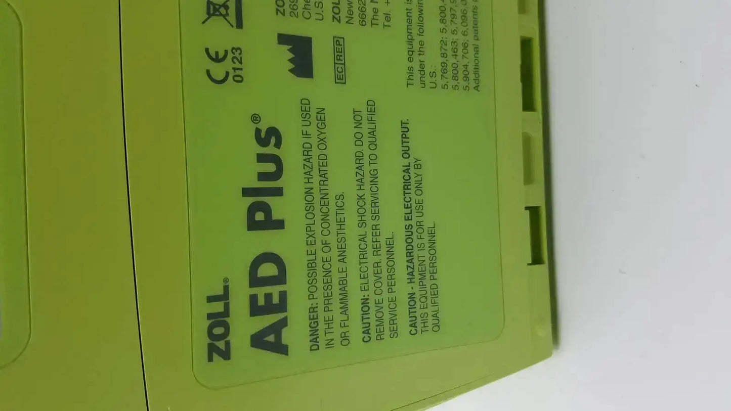 Bright lime green zoll aed plus automated external defibrillator with black text and safety warnings on its label