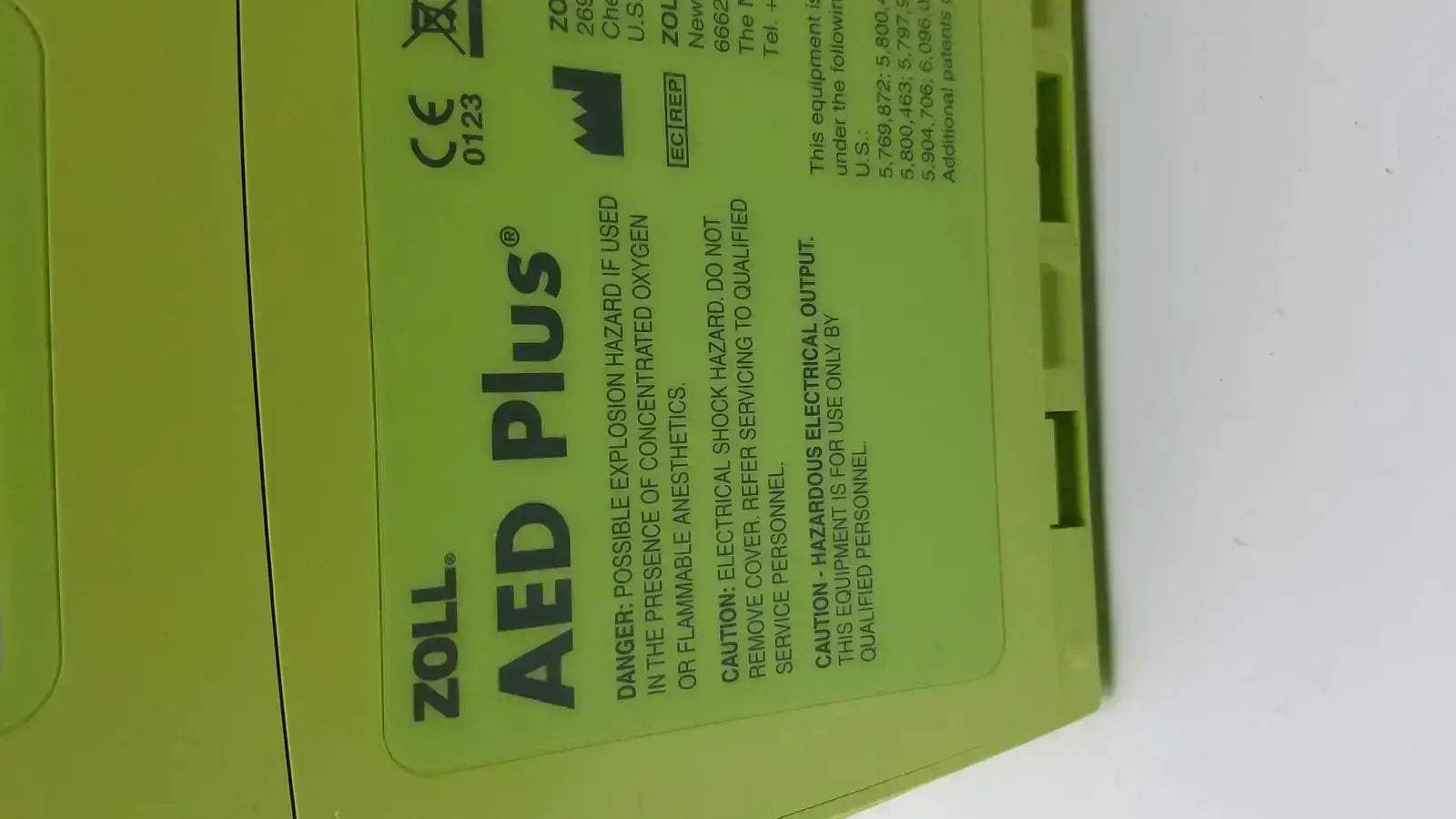 Bright lime green zoll aed plus automated external defibrillator with black text and safety warnings on its label