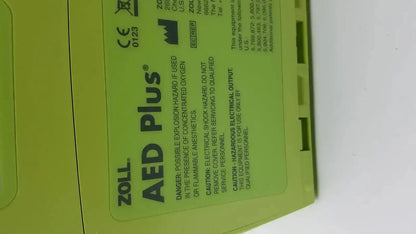 Bright lime green zoll aed plus automated external defibrillator with black text and safety warnings on its label